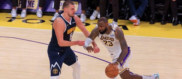 LeBron James najíždí do koše, brání jej Nikola Jokić